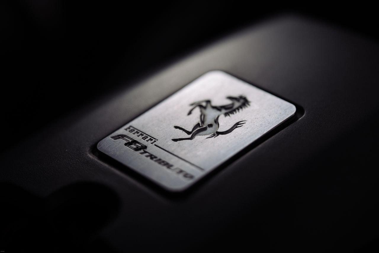 Close-up of a metallic car logo badge with a prancing horse, symbolizing luxury and speed.